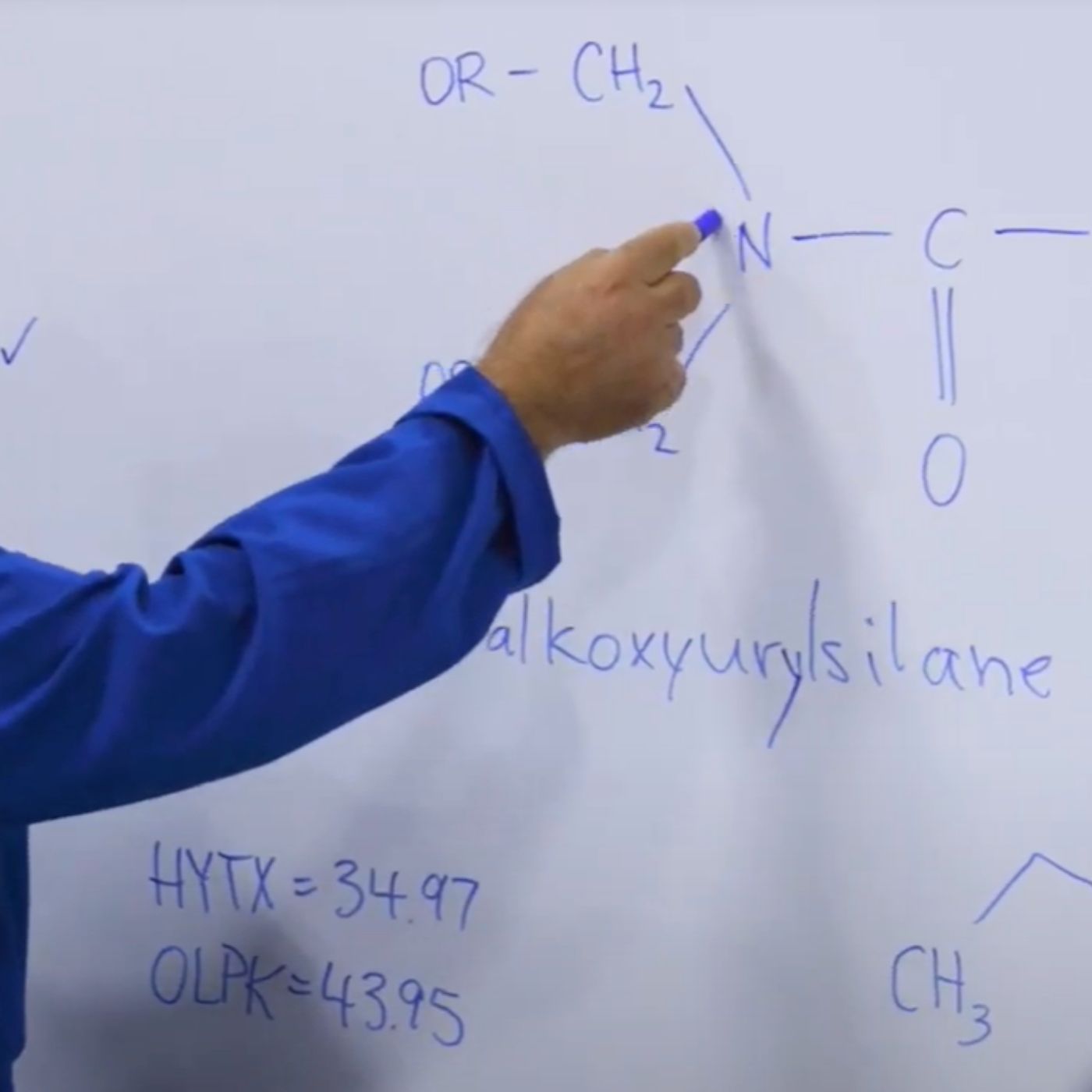 chemist pointing to molecules presented on whiteboard
